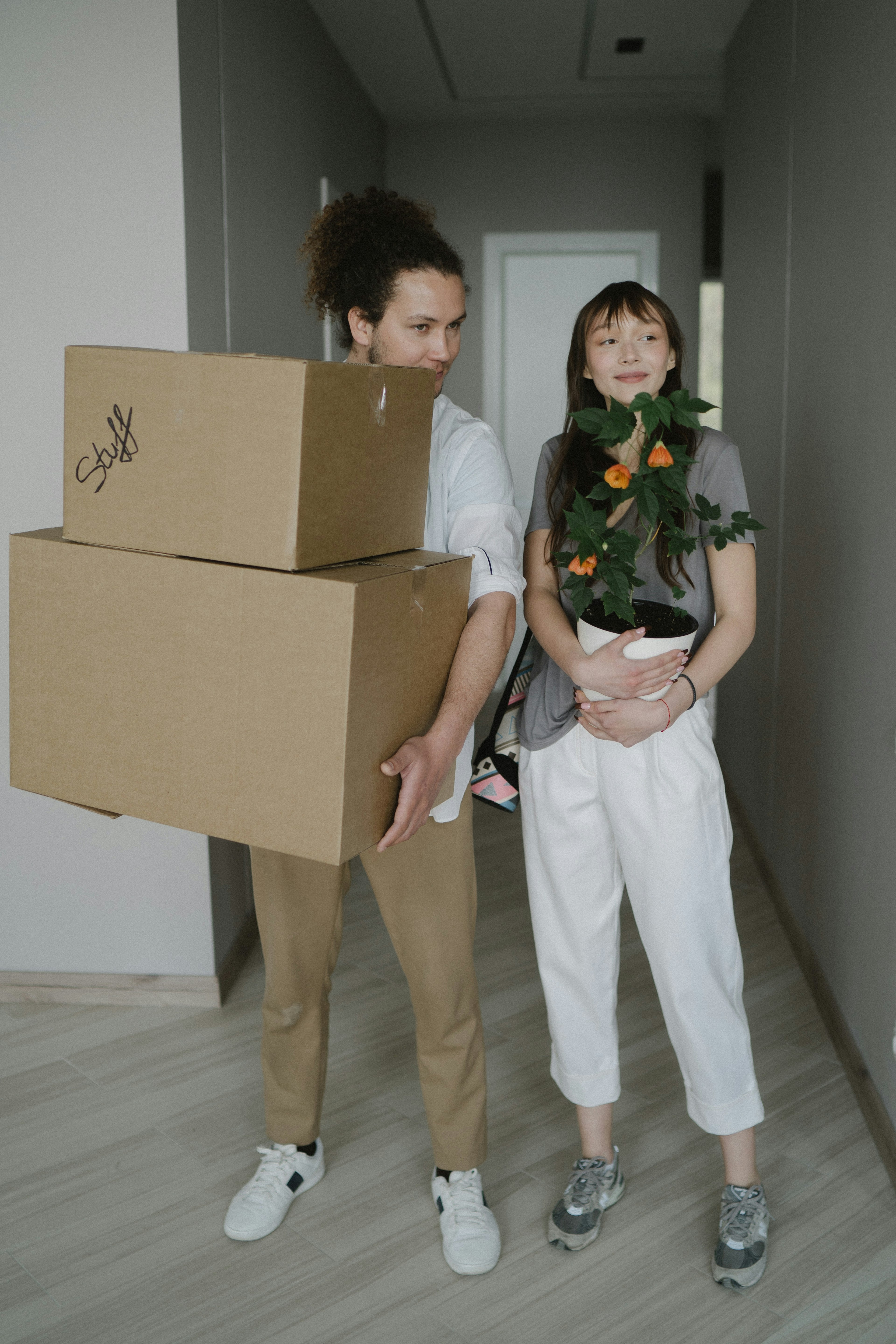 Young couple moving into their first home carrying boxes